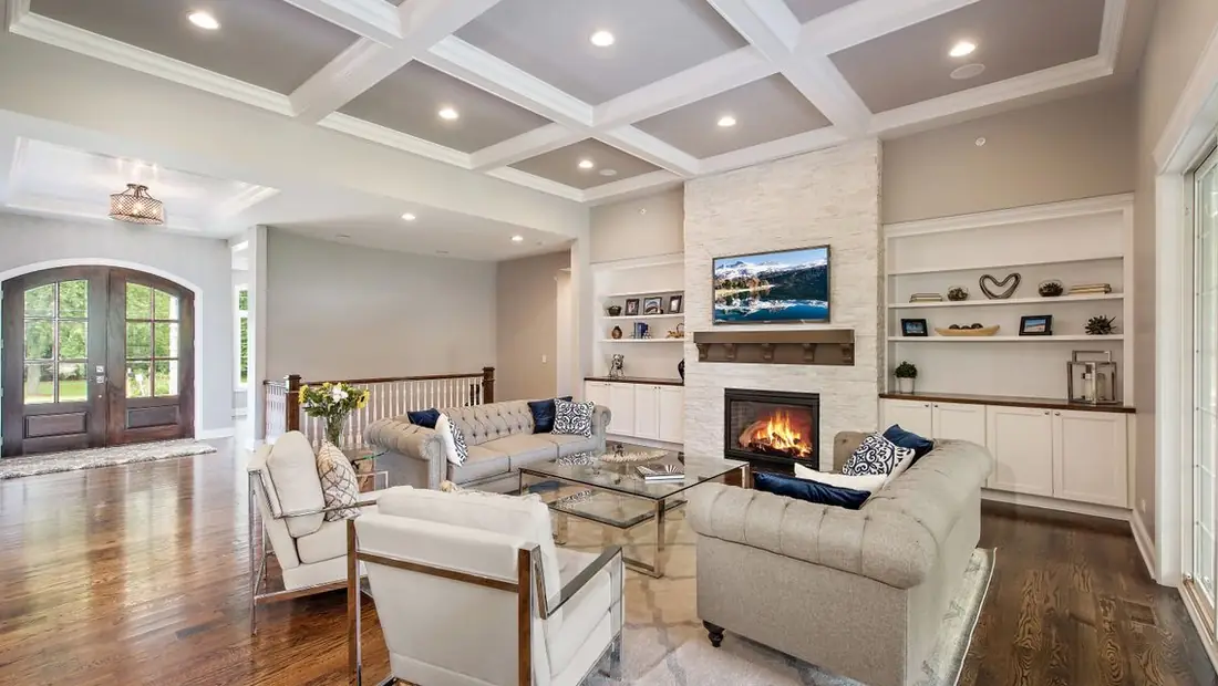 Family room with coffered ceiling and a lit fireplace in a Skycrest custom home