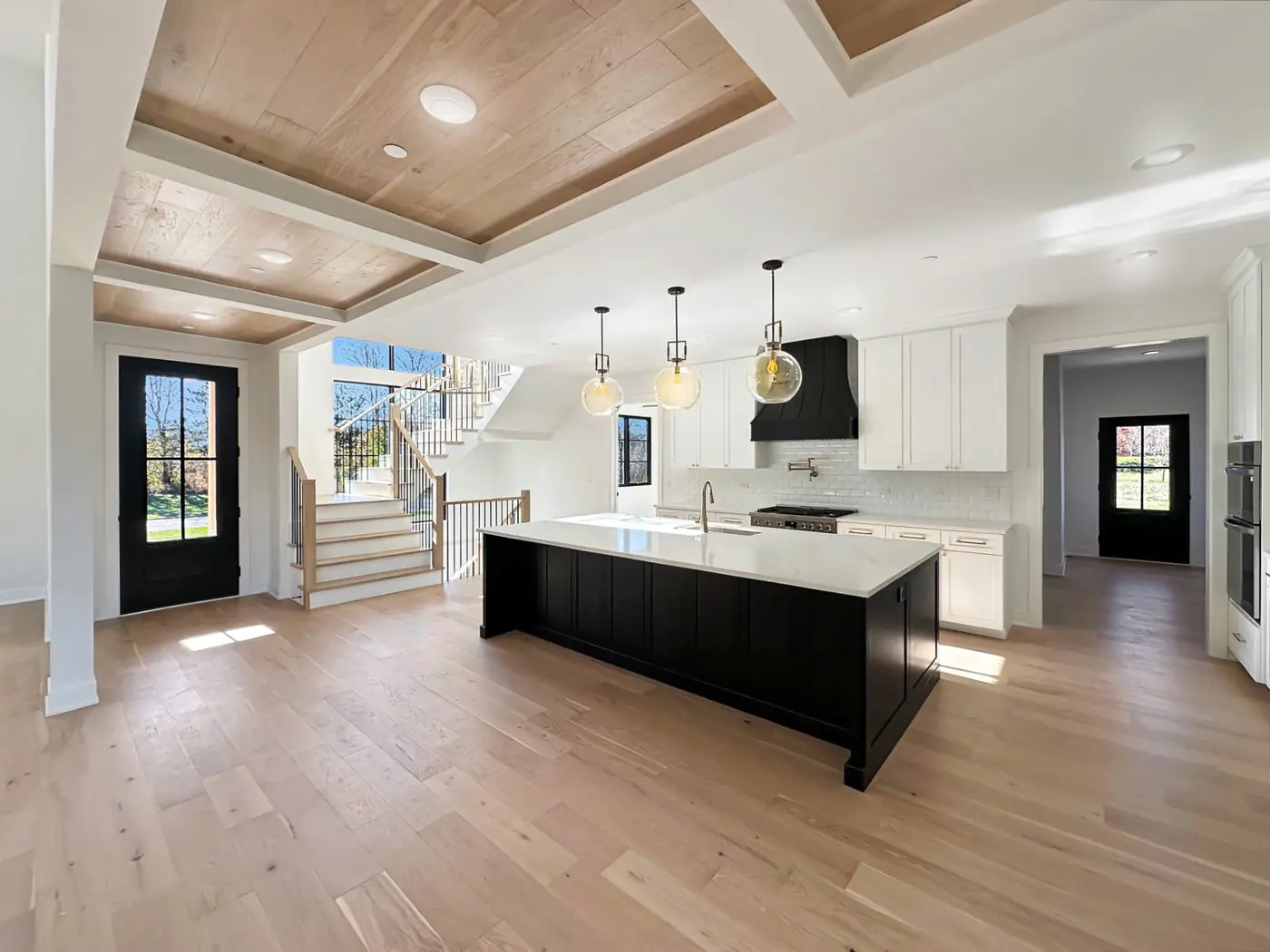 Kitchen with a black island, white counters and pendant lights in a Skycrest custom home