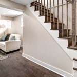 A stairway with a couch and chair at the bottom, showcasing a remodeled basement space for relaxation and comfort.