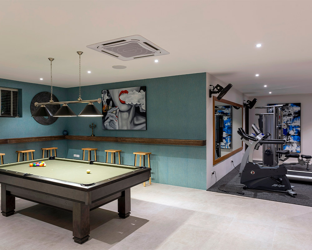 A well-equipped home gym in a basement, showcasing exercise gear and a pool table, emphasizing basement remodeling benefits.
