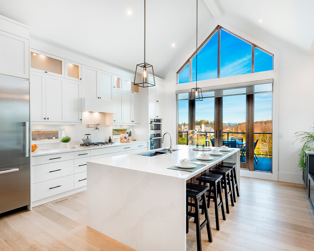 A stylish kitchen with a generous island and panoramic windows offering a glimpse of the beautiful outdoors.