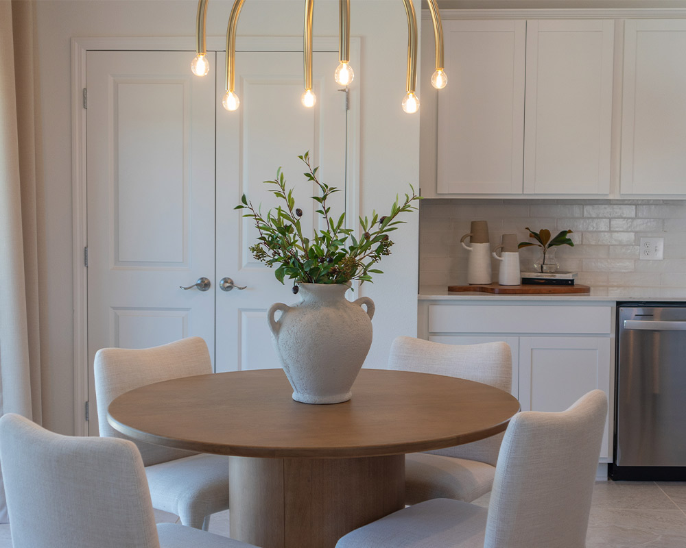 A kitchen table with chairs and a vase, showcasing a cozy dining area in a remodeled home.