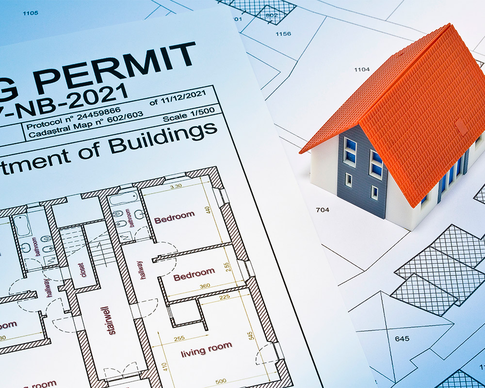 A building permit alongside architectural plans for a custom home, intended for builders in Barrington.