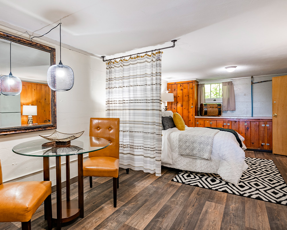 A stylish basement bedroom with a bed, a table, and a mirror, illustrating remodeling concepts for homes in Naperville.