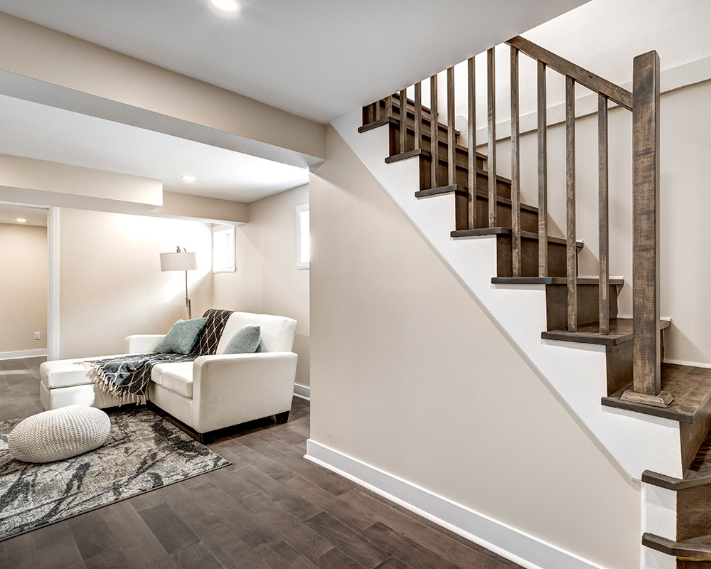 A stylish living room with a couch and stairs, illustrating basement remodeling concepts for homes in Naperville.