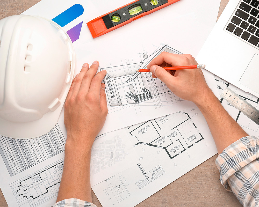 Individual wearing a hard hat works on a laptop, focused on planning a basement remodel in Hinsdale.