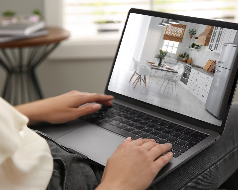 A woman on her laptop, viewing kitchen layouts as she investigates new home construction costs in South Barrington.