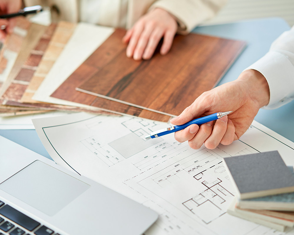 Individual using a laptop and blue pen to research factors affecting home extension costs in Elmhurst.