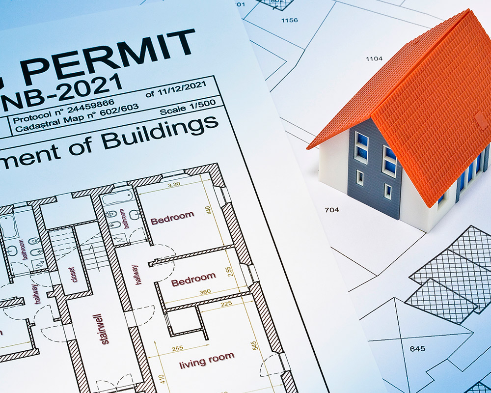 A building permit alongside detailed house plans, illustrating important elements influencing Elmhurst home extension expenses.