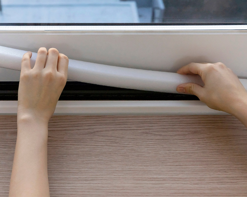 A person sealing a window, isolation. demonstrating winter-proofing techniques for basements in Chicagoland.